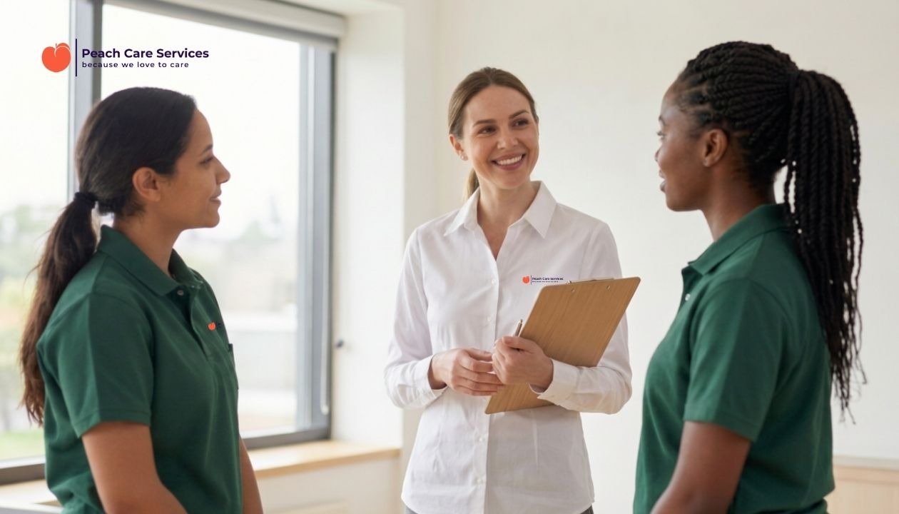 Three care professionals smiling and discussing care staff training at Peach Care Milton Keynes.