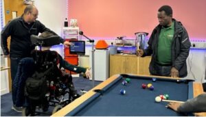 Newsletter 2 Peach Care Services staff supporting an individual in a wheelchair using assistive technology to break communication barriers in Milton Keynes.